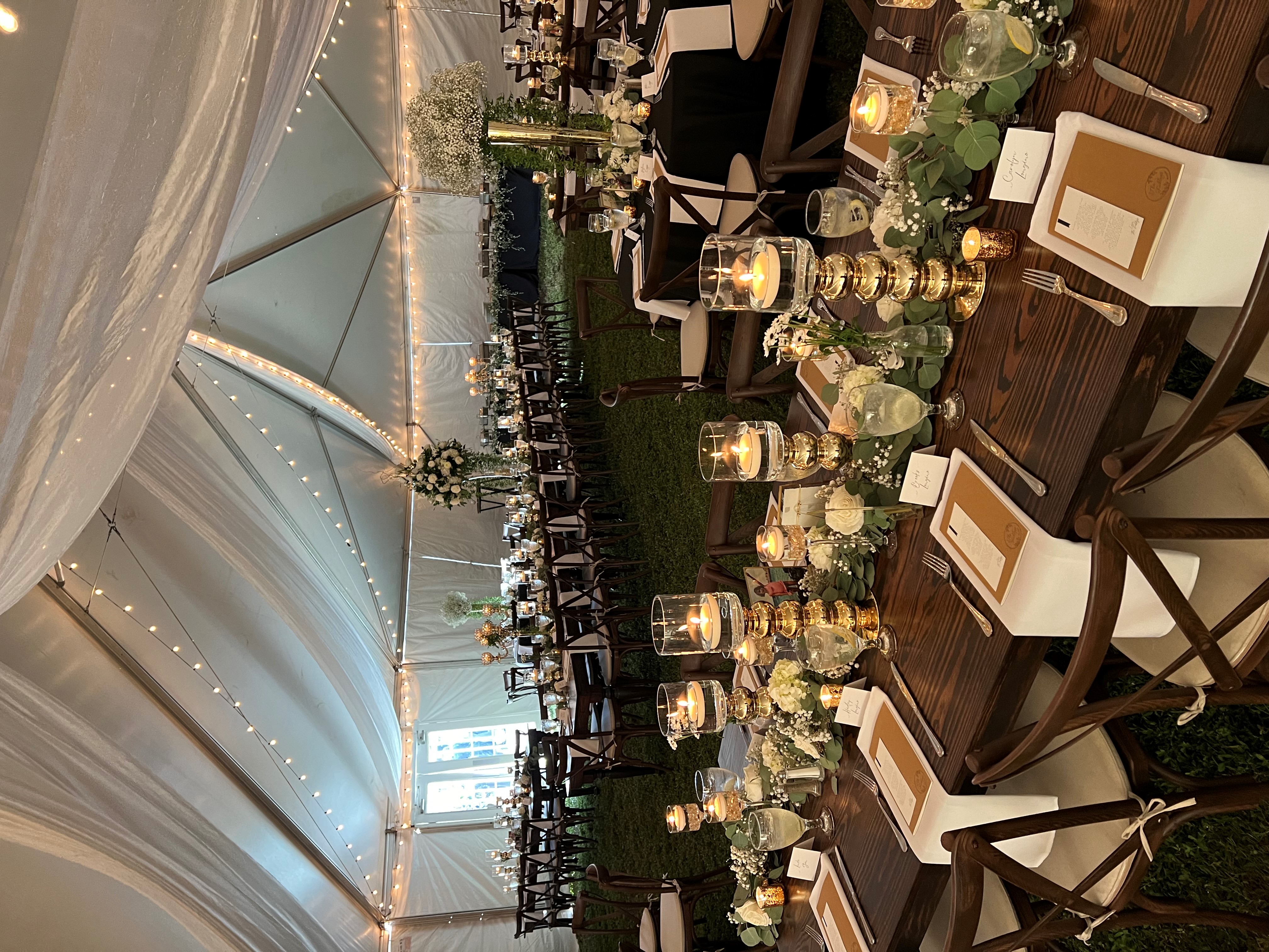 Tented wedding reception with white flowers, lush greenery and candles