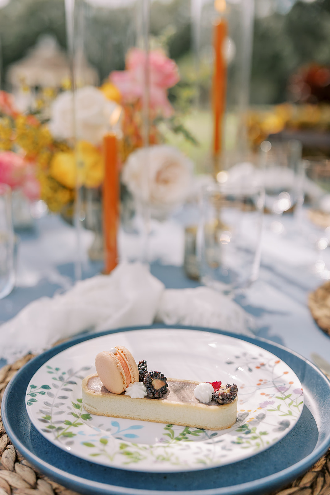 Dessert served on floral china with orange candles and bright floral centerpiece
