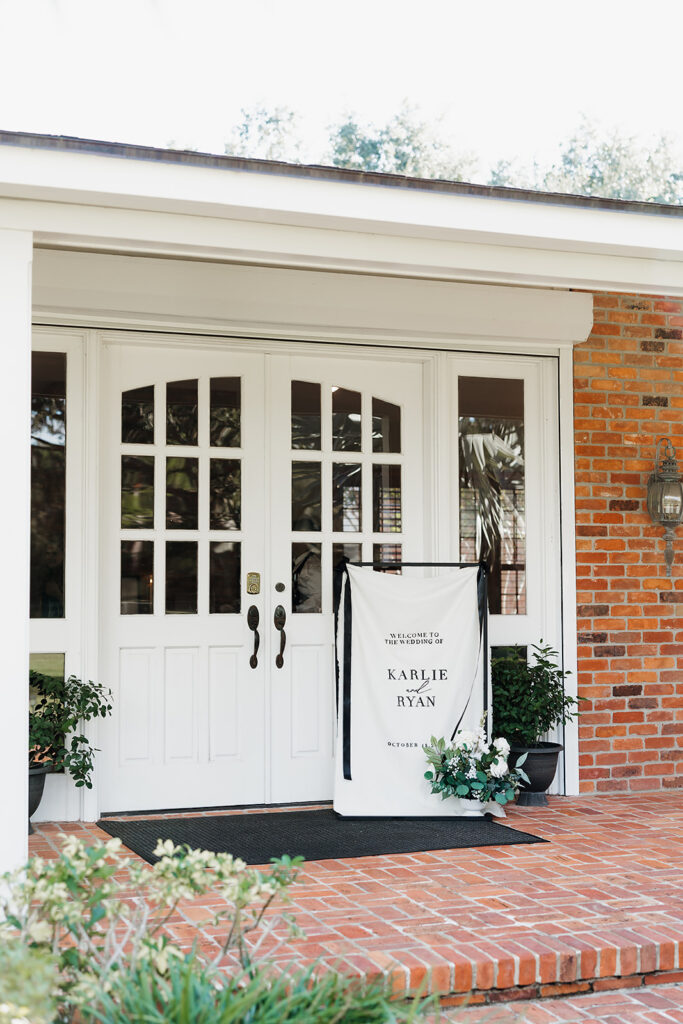 Cloth welcome sign and floral arrangement outside front doors