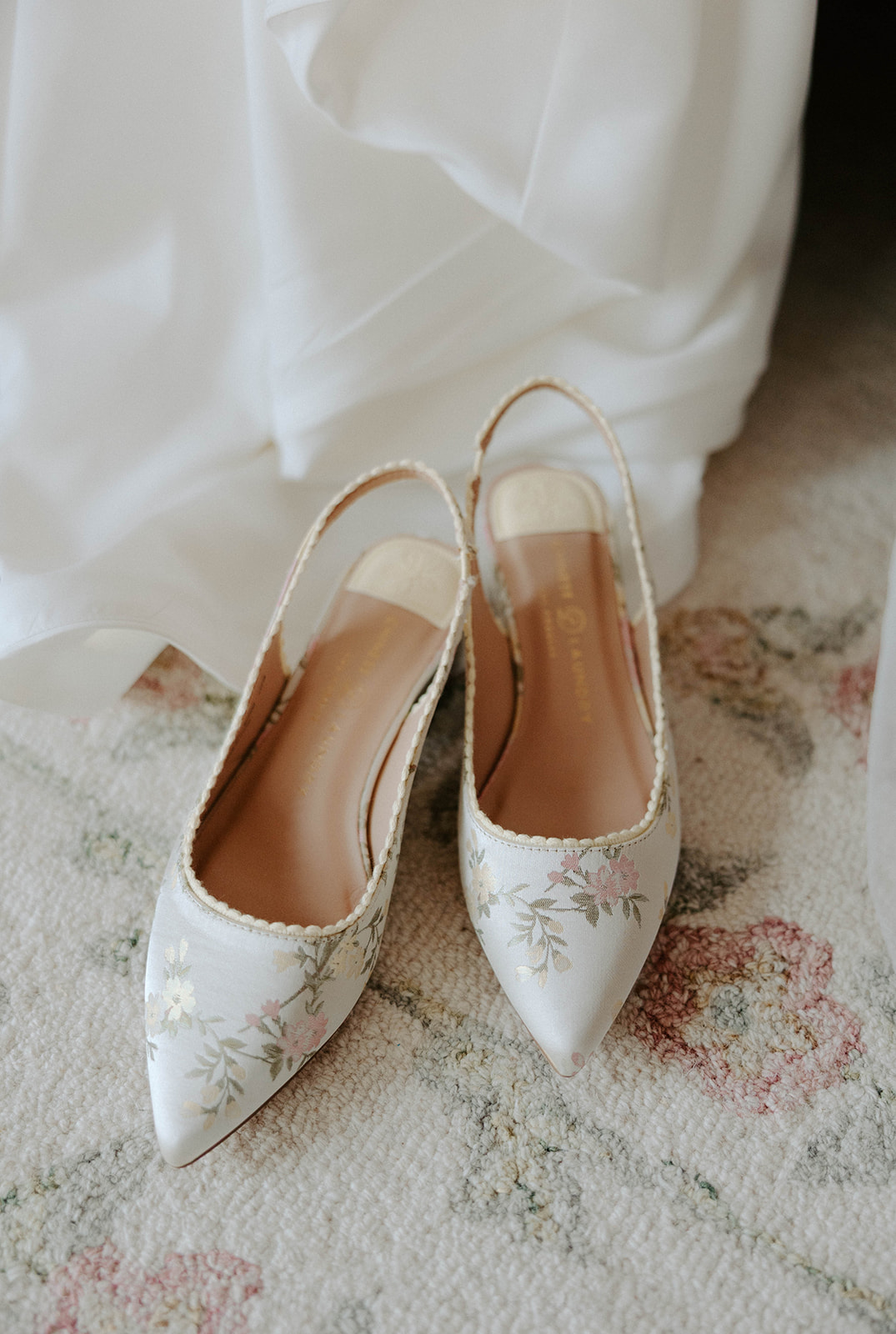Bride's wedding shoes with floral print match the rug in the bridal suite