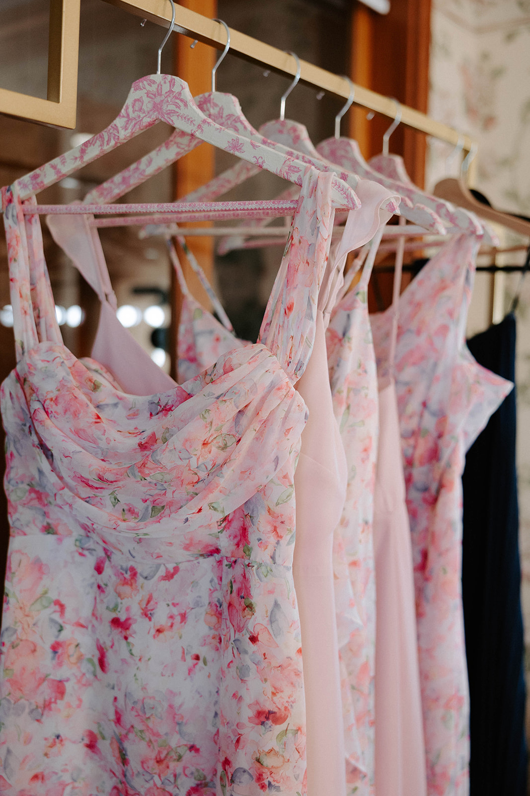 Bridesmaids dresses in pink floral patterns on hanging rack