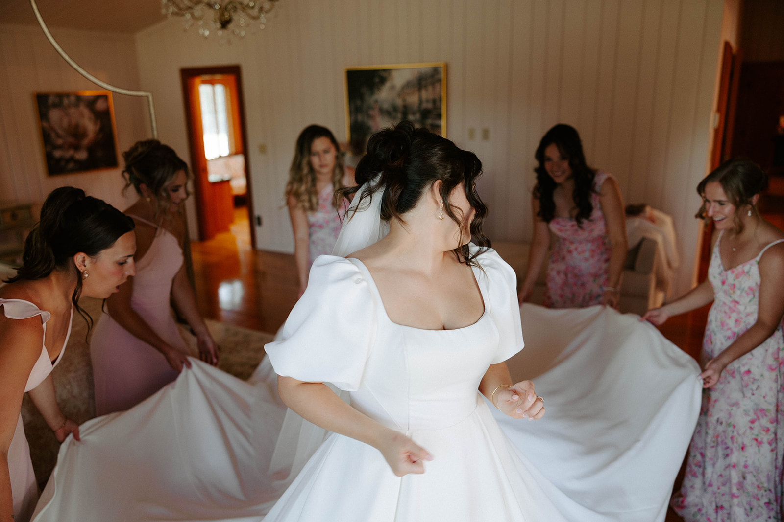 Bridesmaids fluffing bride's wedding dress