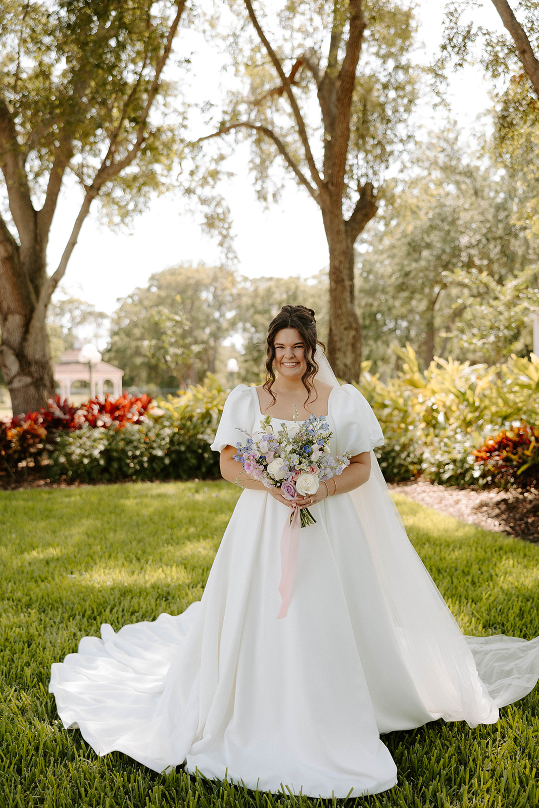 Bride holding spring bouquet under oak trees