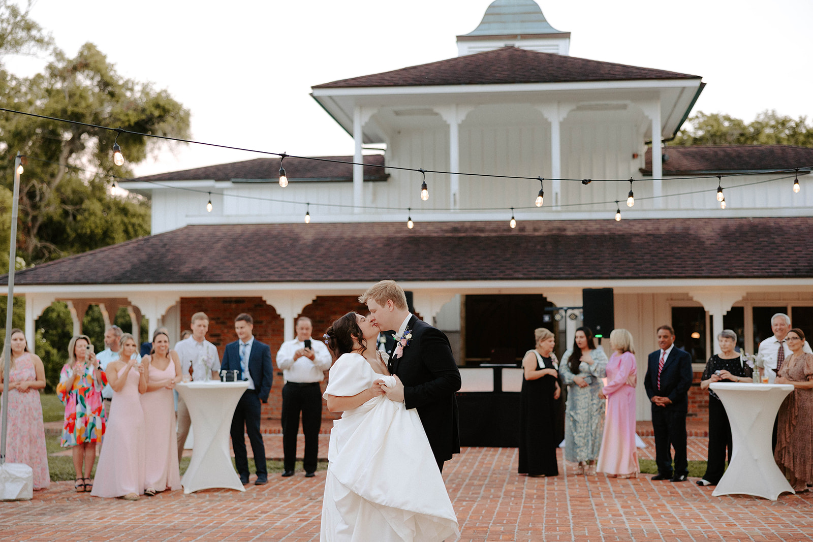 Bride and Groom dancing first dance under bistro lights in front of barn