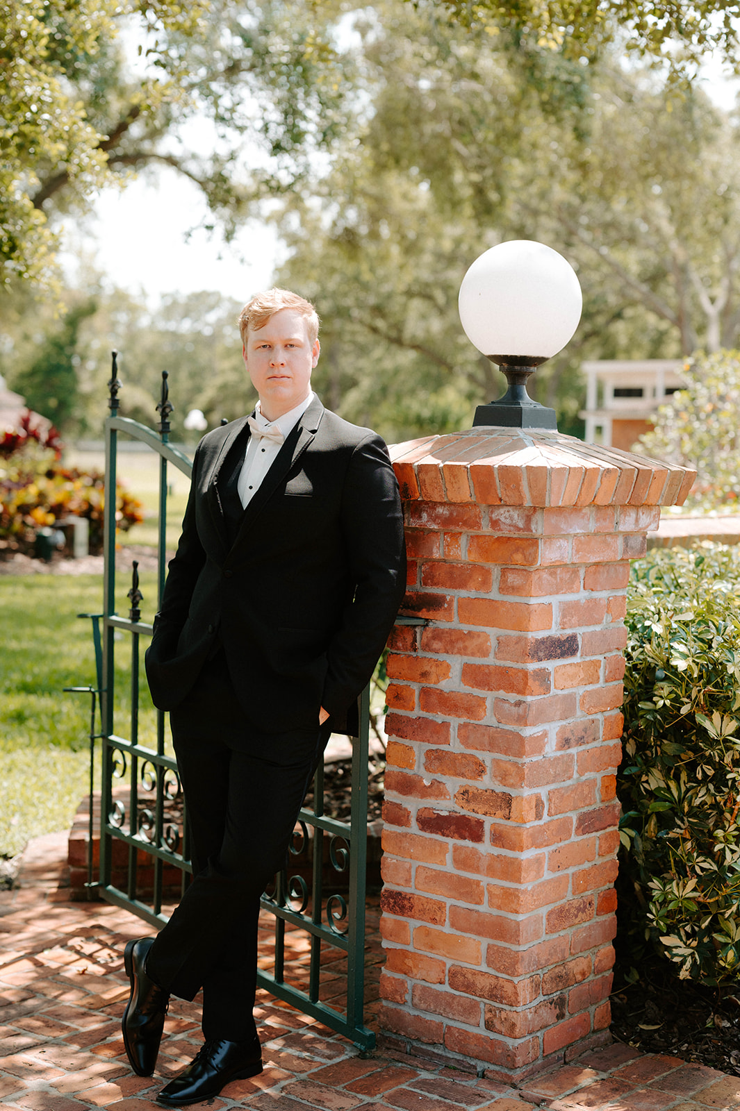 Groom leaning against bright light post