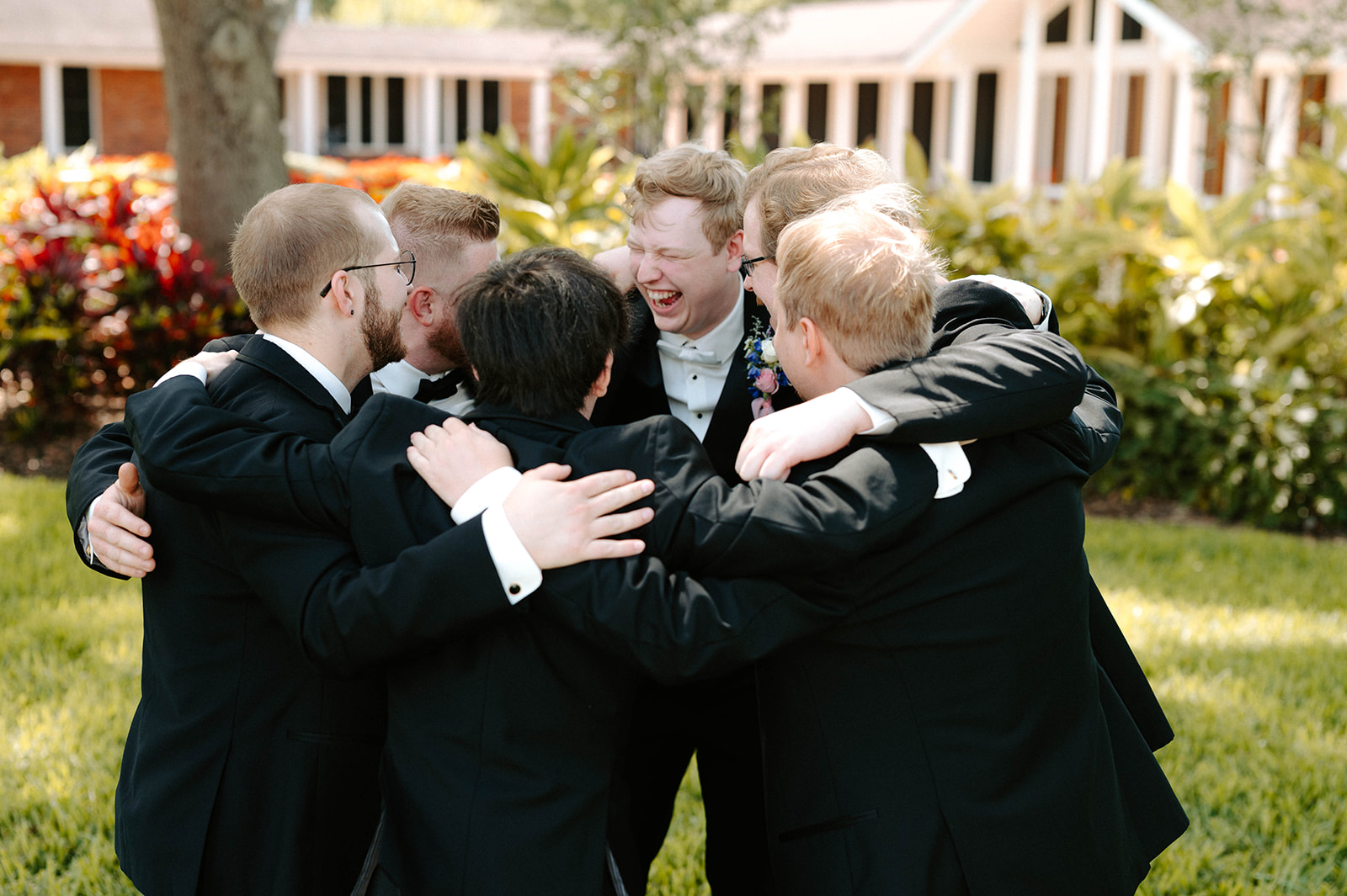 Groom and groomsmen hugging on the lawn