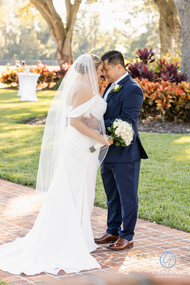 Bride and groom with heads together and southern landscaping behind them